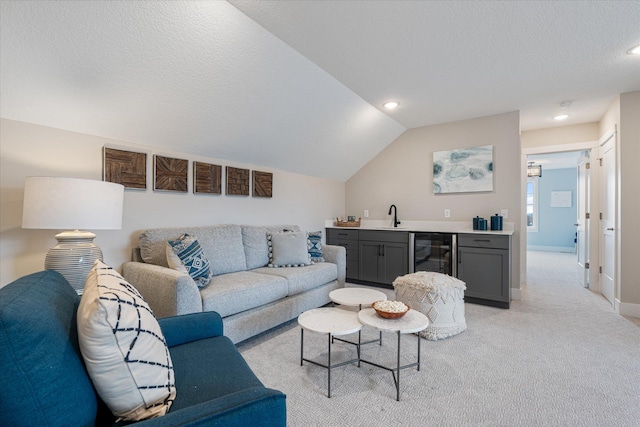 carpeted living room with a textured ceiling, indoor wet bar, wine cooler, and lofted ceiling