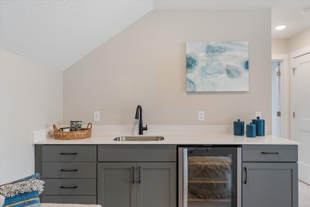 bar with sink, wine cooler, gray cabinetry, and lofted ceiling