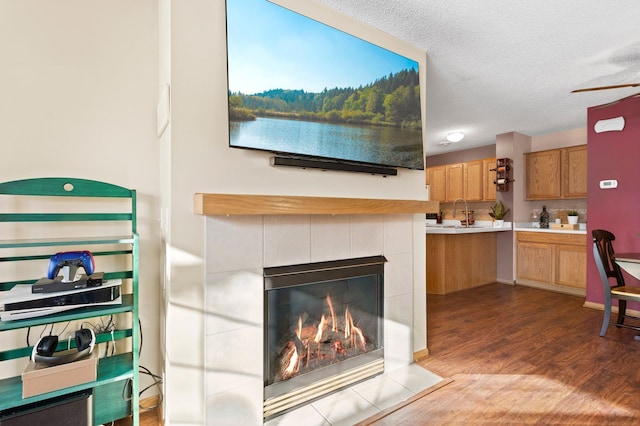 living room with a fireplace, hardwood / wood-style floors, sink, and a textured ceiling