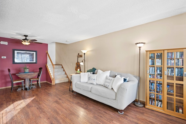 living room with ceiling fan, a textured ceiling, and dark hardwood / wood-style flooring