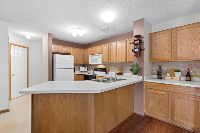 kitchen with sink, white appliances, kitchen peninsula, and dark wood-type flooring