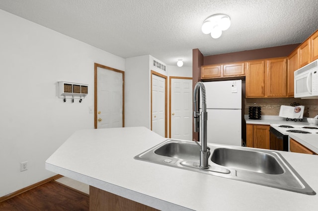 kitchen with white appliances, a textured ceiling, tasteful backsplash, sink, and dark hardwood / wood-style floors