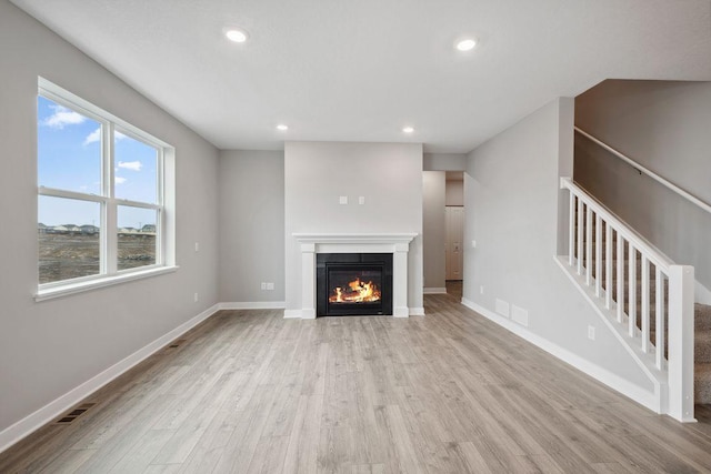 13617 Aulden Ave, Rosemount, MN 55068 - unfurnished living room featuring light wood-type flooring, baseboards, a glass covered fireplace, recessed lighting, and stairway