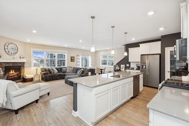 kitchen featuring appliances with stainless steel finishes, a kitchen island with sink, white cabinets, and decorative light fixtures