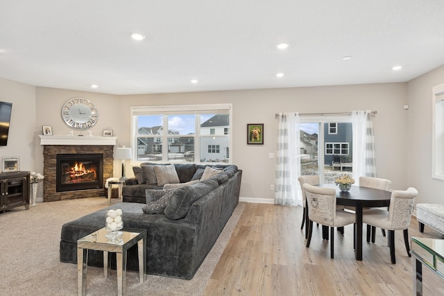 living room with a stone fireplace and light wood-type flooring