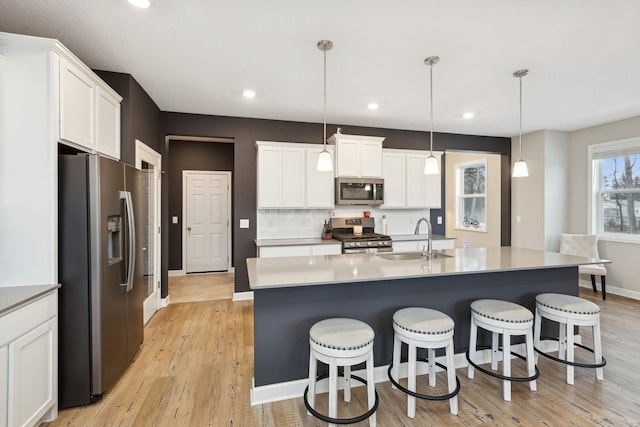 kitchen with pendant lighting, sink, appliances with stainless steel finishes, backsplash, and white cabinets