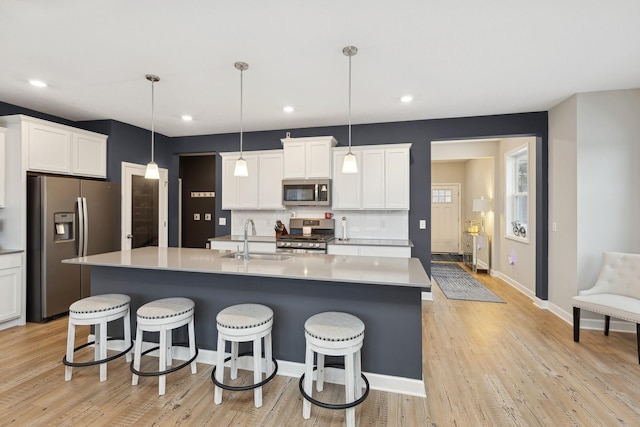 kitchen with pendant lighting, sink, white cabinetry, stainless steel appliances, and tasteful backsplash