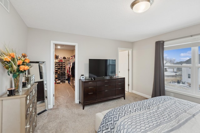 carpeted bedroom with a spacious closet and a closet