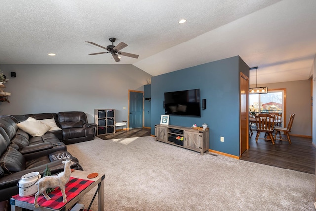 living room with carpet floors, a textured ceiling, ceiling fan with notable chandelier, and vaulted ceiling