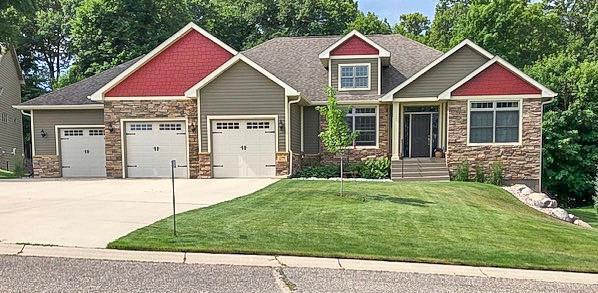 craftsman-style house with an attached garage, driveway, stone siding, and a front yard