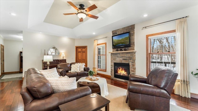 living area with recessed lighting, a fireplace, wood finished floors, baseboards, and a raised ceiling