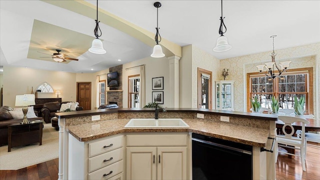 kitchen with a sink, black dishwasher, open floor plan, dark wood finished floors, and pendant lighting