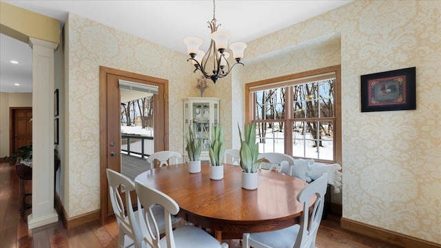 dining space with wallpapered walls, baseboards, wood finished floors, and ornate columns