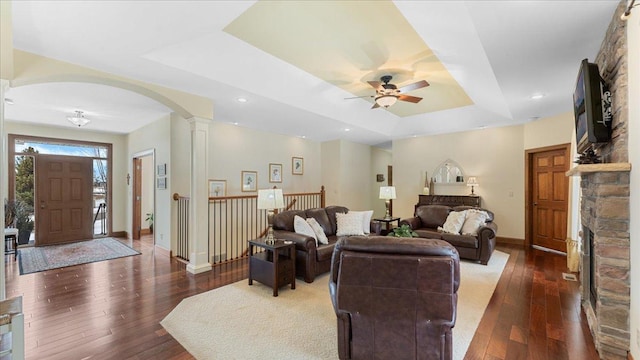 living room with decorative columns, baseboards, a raised ceiling, and dark wood-style flooring