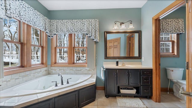 bathroom featuring toilet, vanity, baseboards, a jetted tub, and tile patterned floors