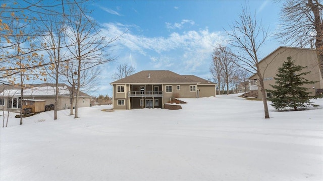 snow covered back of property featuring a garage