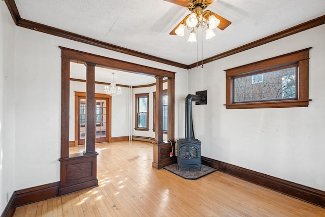 unfurnished living room with wood-type flooring, a wood stove, a textured ceiling, and ornamental molding