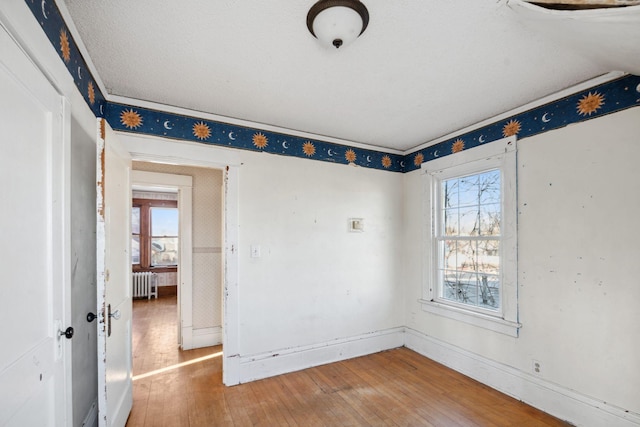 unfurnished room featuring radiator heating unit and hardwood / wood-style floors