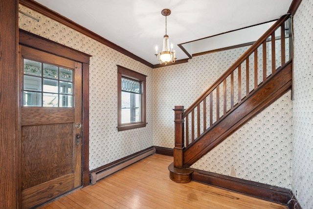 foyer entrance featuring hardwood / wood-style flooring, a baseboard radiator, crown molding, and a notable chandelier