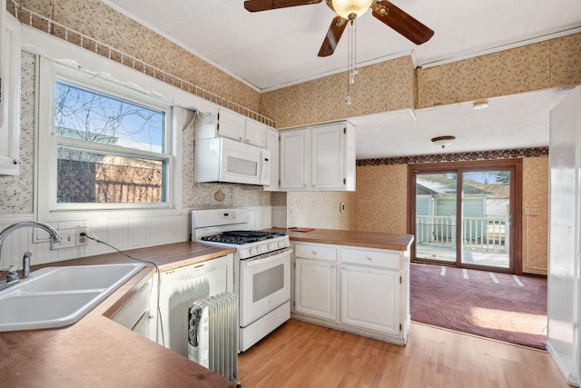 kitchen featuring white cabinetry, sink, light hardwood / wood-style floors, kitchen peninsula, and white appliances