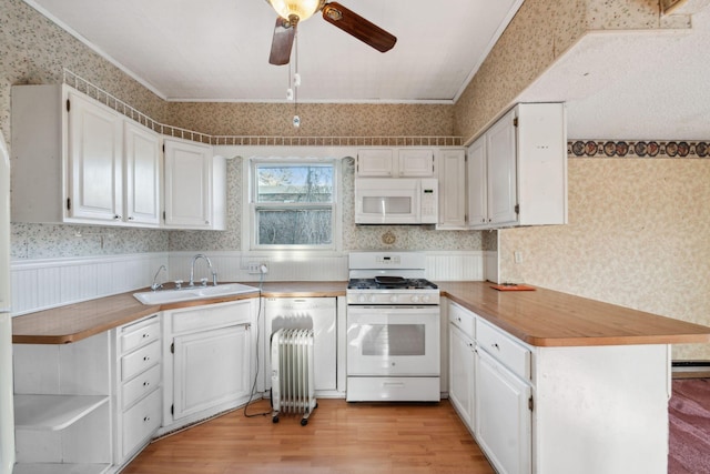 kitchen with white cabinetry, white appliances, light hardwood / wood-style floors, and sink