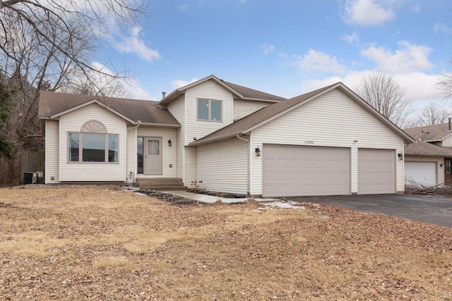 tri-level home featuring entry steps, roof with shingles, driveway, and an attached garage