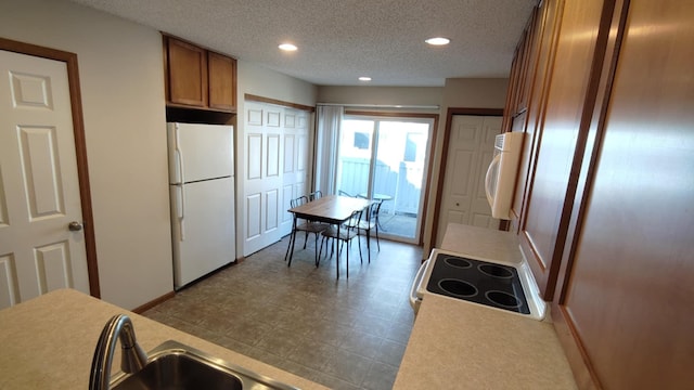 kitchen with freestanding refrigerator, electric range oven, brown cabinetry, fridge, and recessed lighting