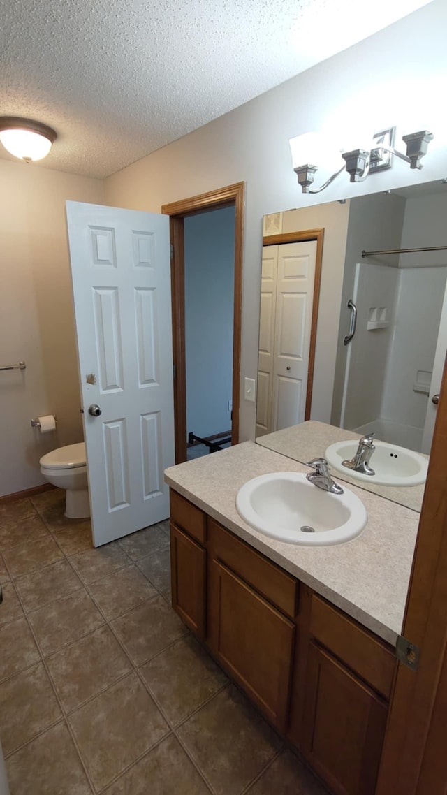 full bathroom with toilet, a textured ceiling, tile patterned floors, vanity, and a shower