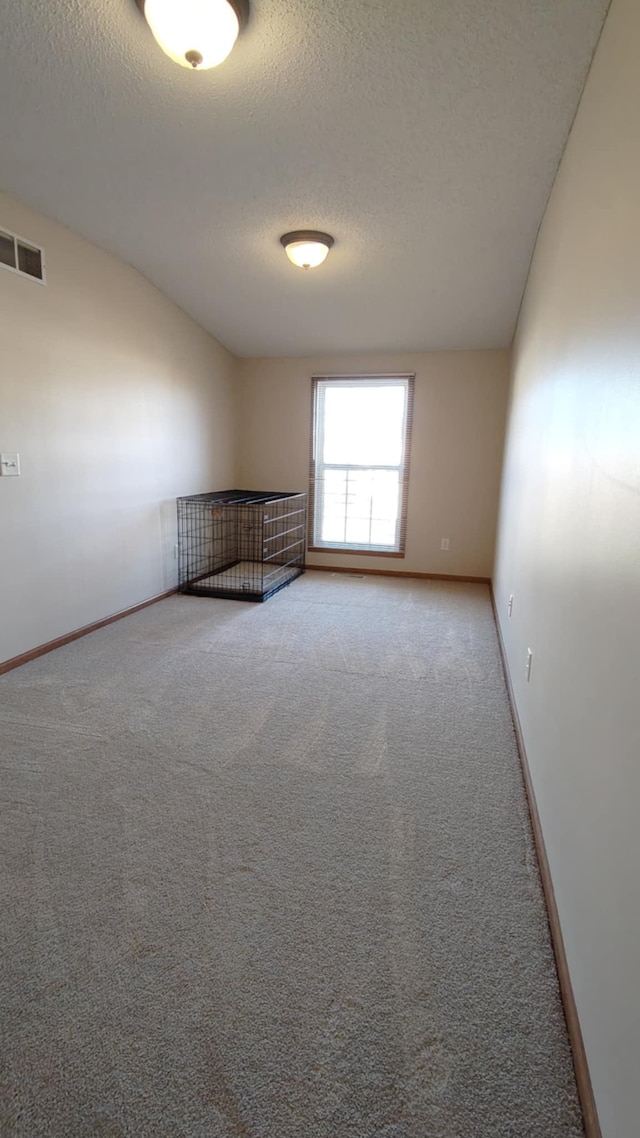 empty room with carpet, a textured ceiling, and baseboards