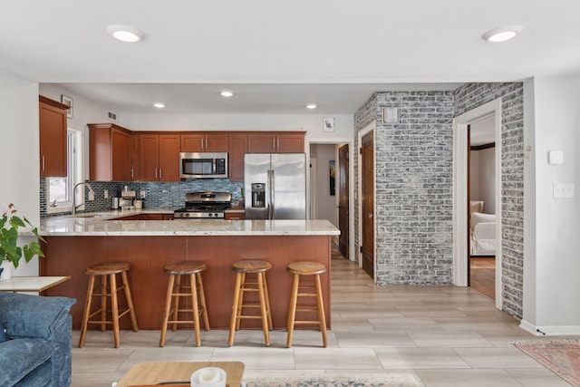 kitchen with sink, appliances with stainless steel finishes, tasteful backsplash, light stone countertops, and kitchen peninsula