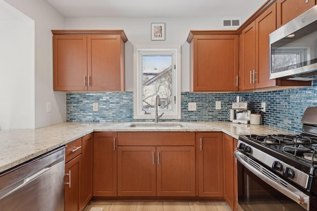 kitchen featuring tasteful backsplash, sink, stainless steel appliances, and light stone countertops