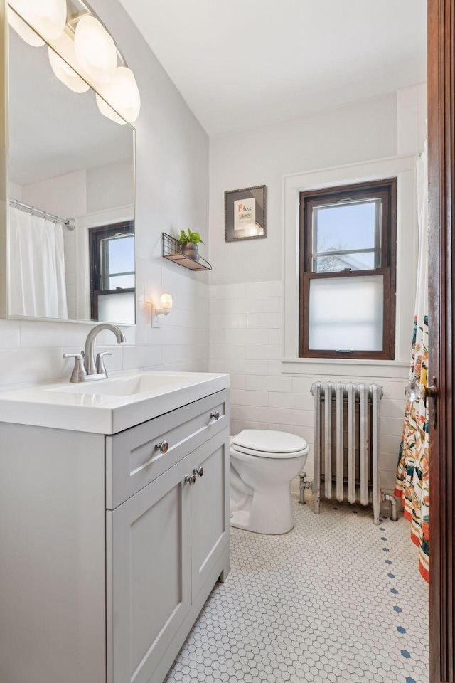 bathroom with vanity, radiator heating unit, tile walls, and toilet