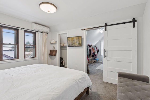 bedroom with an AC wall unit, carpet floors, a walk in closet, a barn door, and a closet