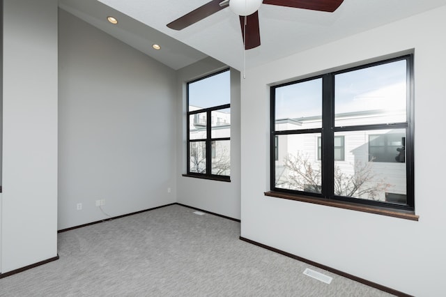 empty room with light colored carpet, lofted ceiling, and a wealth of natural light