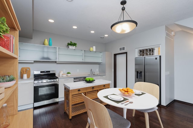 kitchen with appliances with stainless steel finishes, sink, dark wood-type flooring, and decorative light fixtures