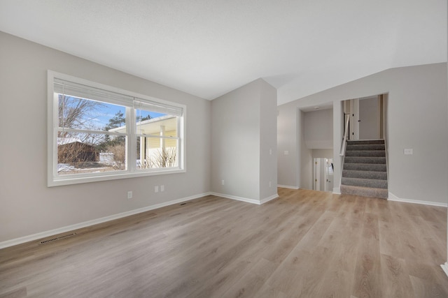 unfurnished living room with lofted ceiling and light wood-type flooring