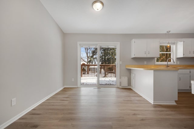 kitchen with white cabinetry, a healthy amount of sunlight, sink, and light wood-type flooring