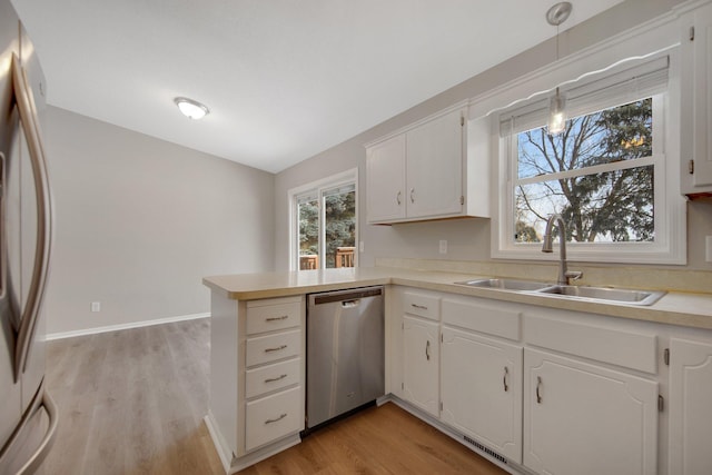 kitchen featuring pendant lighting, stainless steel appliances, kitchen peninsula, and white cabinets