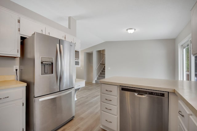 kitchen with lofted ceiling, stainless steel appliances, white cabinets, and light wood-type flooring