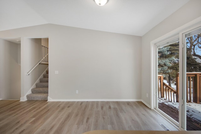 spare room with lofted ceiling and light hardwood / wood-style flooring