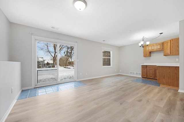 unfurnished living room with an inviting chandelier and light wood-type flooring