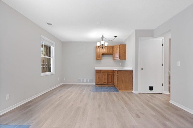 kitchen with light hardwood / wood-style flooring, a chandelier, and decorative light fixtures