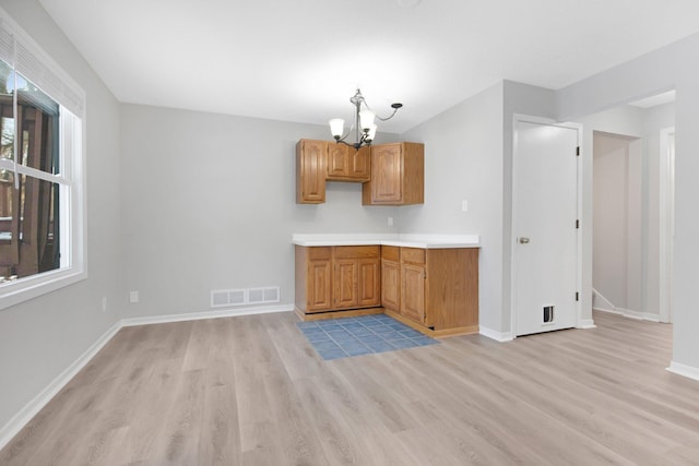 kitchen featuring light wood-type flooring, a healthy amount of sunlight, a chandelier, and decorative light fixtures