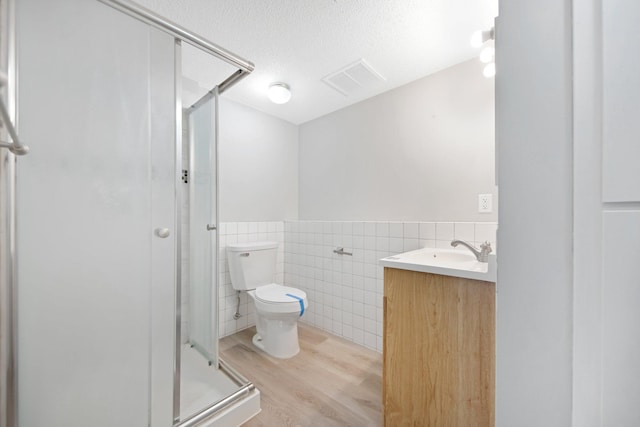 bathroom with toilet, a textured ceiling, tile walls, vanity, and hardwood / wood-style flooring