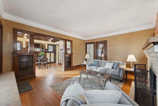 living room featuring crown molding, light hardwood / wood-style floors, and decorative columns