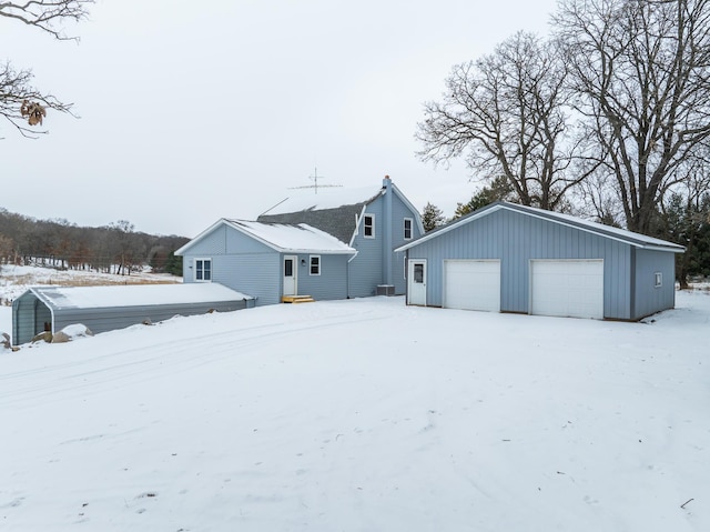 snow covered back of property with an outbuilding and a garage