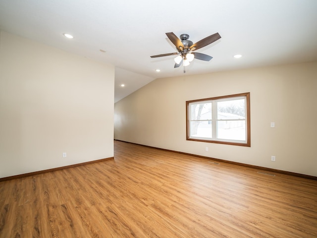 spare room with ceiling fan, vaulted ceiling, and light wood-type flooring