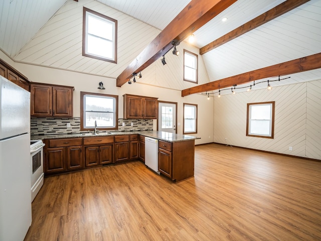 kitchen with white appliances, kitchen peninsula, sink, and light hardwood / wood-style flooring