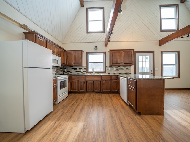 kitchen featuring decorative backsplash, a center island, light hardwood / wood-style floors, light stone counters, and white appliances