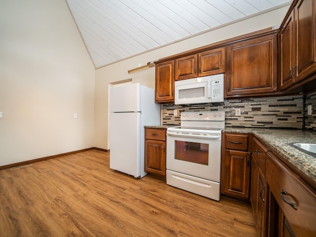 kitchen with tasteful backsplash, light hardwood / wood-style flooring, white appliances, and dark stone counters